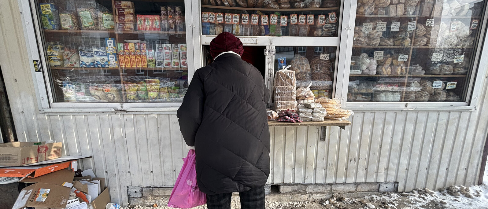 Eine Person steht vor einem kleinen Kiosk und kauft Lebensmittel.