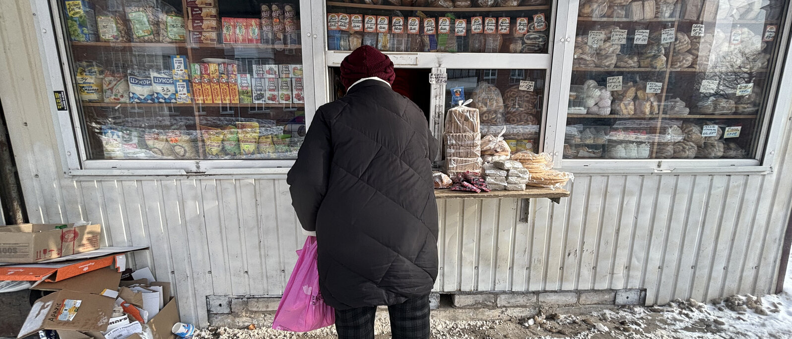 Eine Person steht vor einem kleinen Kiosk und kauft Lebensmittel.
