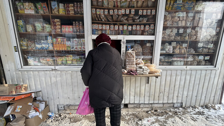 Eine Person steht vor einem kleinen Kiosk und kauft Lebensmittel.