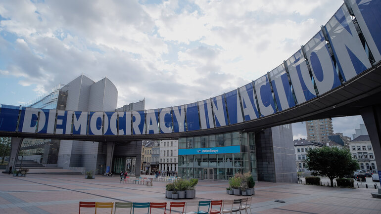 Ein großes, gebogenes Banner zeigt den Schriftzug "Democracy in Action". 