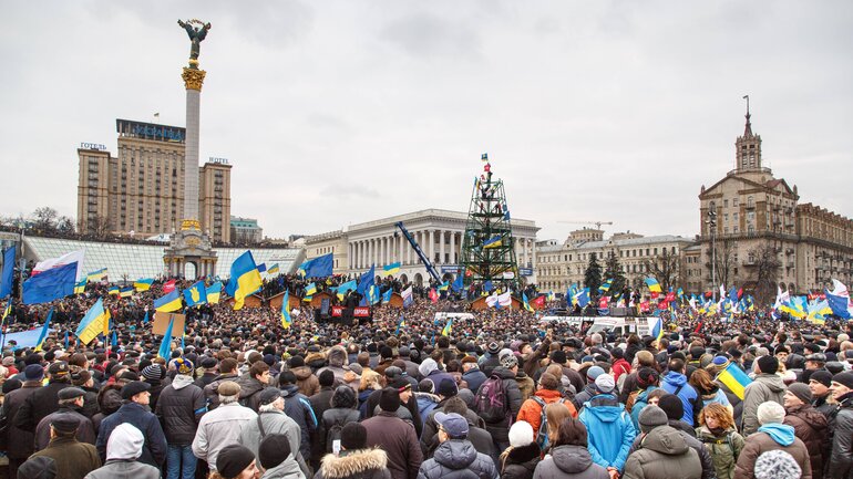 Der Maidan-Platz in Kiew, erkennbar an der großen weißen Säule mit dem Engel, ist voll von Menschen, die ukrainische Fahnen schwenken.
