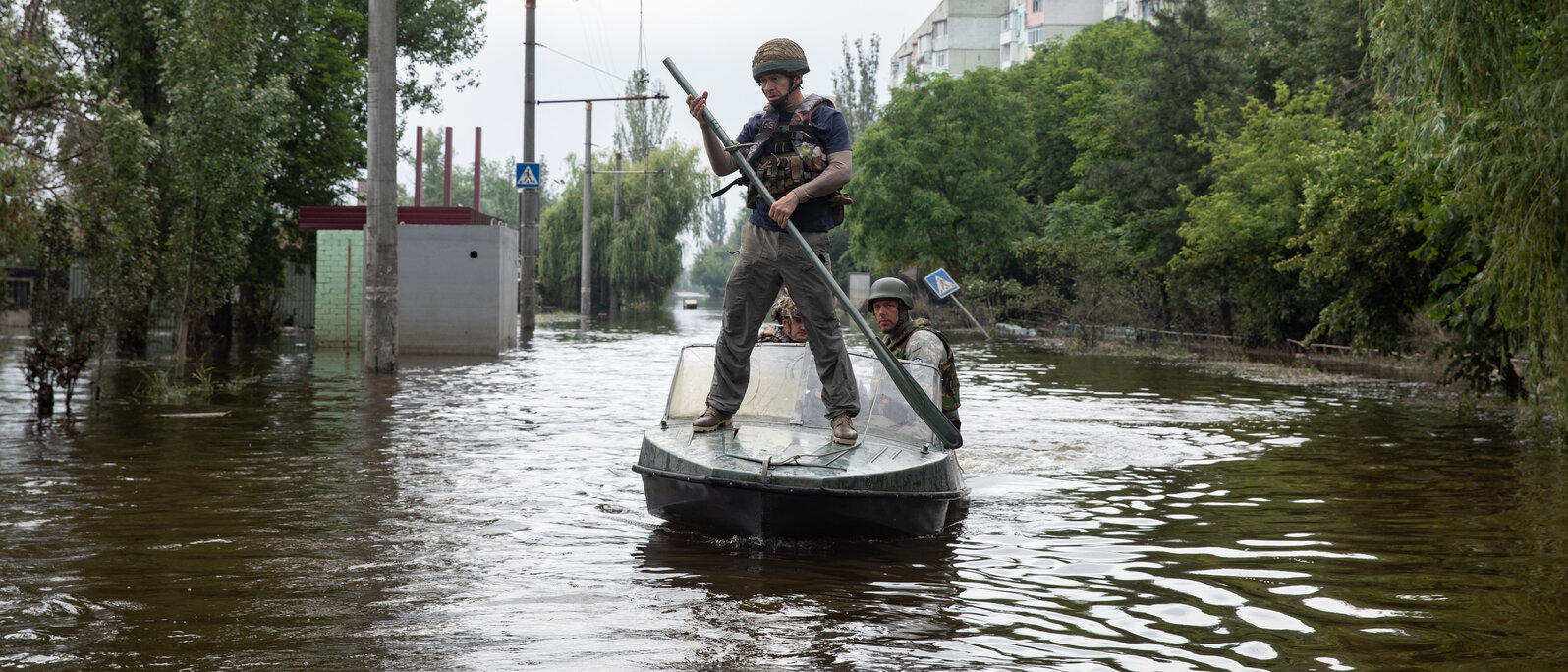 Ein Mann mit einem Ruder steht auf einem Boot, das durch eine überflutete Straße fährt