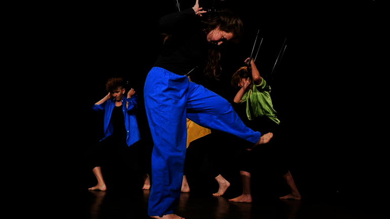 Four people are performing on a stage in front of a black background.