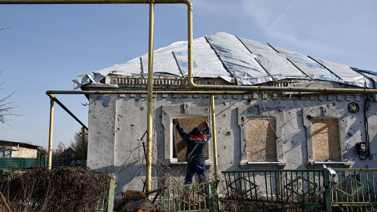 A man boards up a window damaged by Russian shelling with a piece of particle board in front-line Orikhiv, Polohy district, Zaporizhzhia region, southeastern Ukraine, on February 12, 2025.