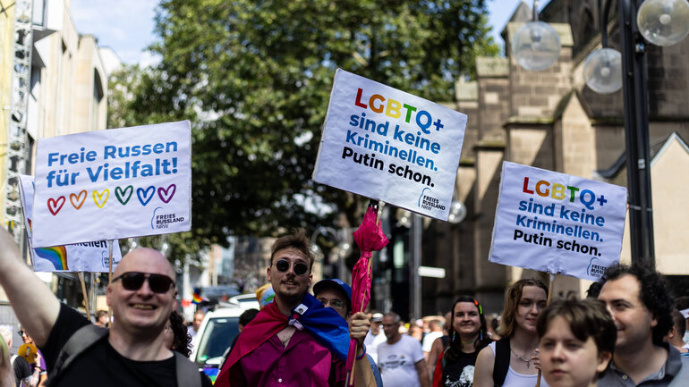 Aktivist*innen halten Schilder der Initiative ‚Freies Russland NRW‘ bei der CSD-Demonstration in Köln.