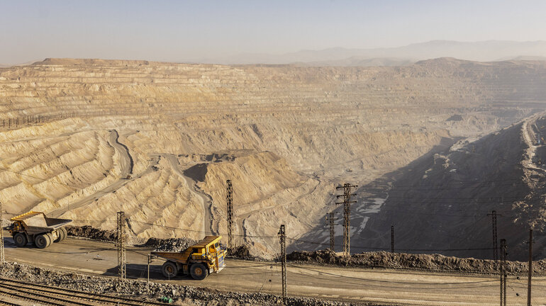 Tipper truck in front of a large open-pit mine.